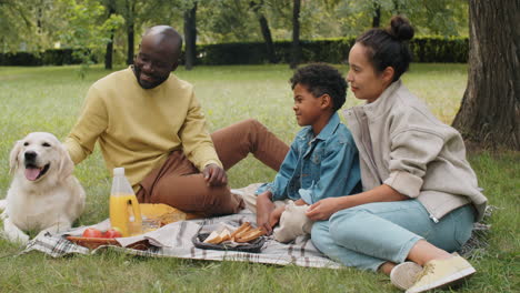 Happy-African-American-Family-Petting-Dog-and-Smiling-at-Camera-in-Park